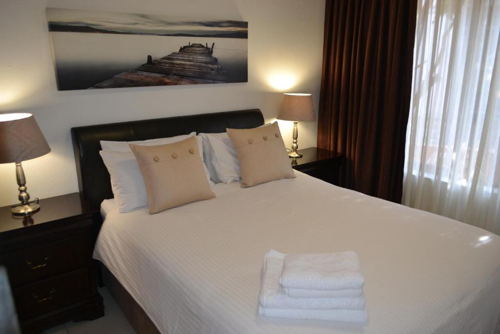 约翰内斯堡Alendo Apartments的卧室配有白色的床和2条毛巾