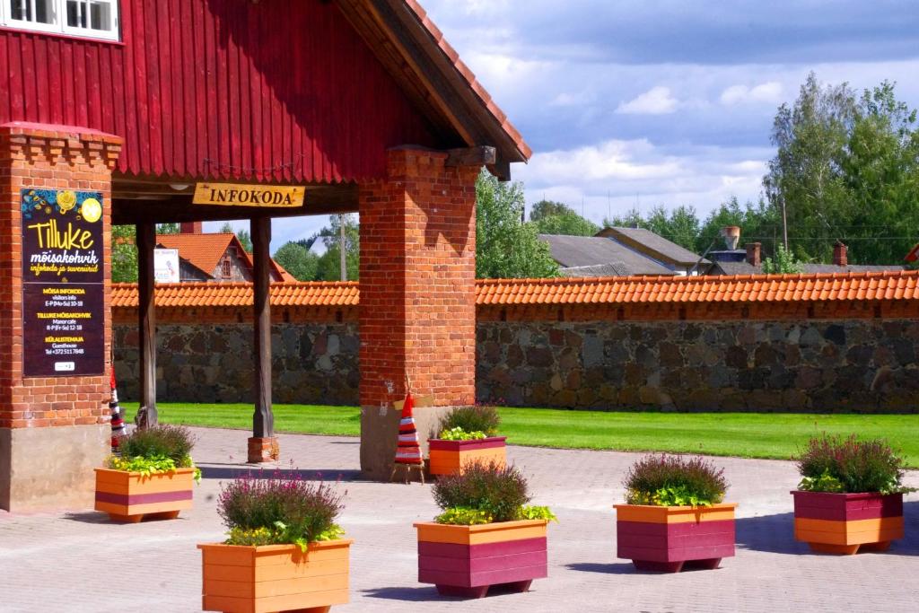 MoosteMooste mõisa Linakoja külalistemaja的一座有红谷仓的建筑,里面种有盆栽植物