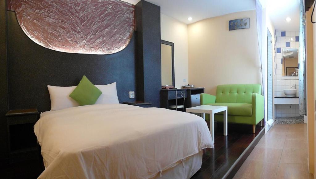 垦丁大街垦丁海晴天旅店的一间卧室配有一张床和一把绿色椅子