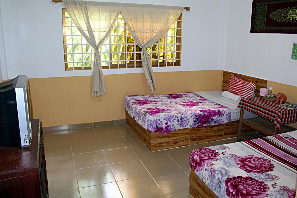 Kampong Chhnang加登旅馆的一间卧室设有两张床和窗户。