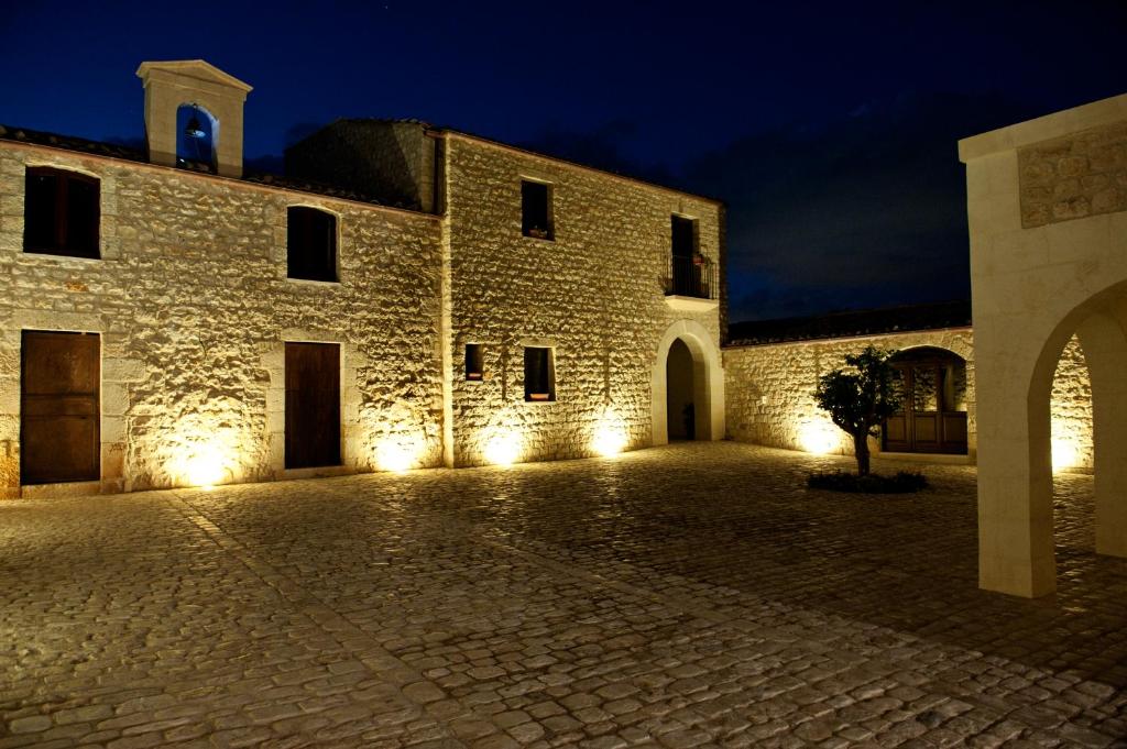 莫迪卡Nacalino Agriturismo的一座大型石头建筑,晚上有灯