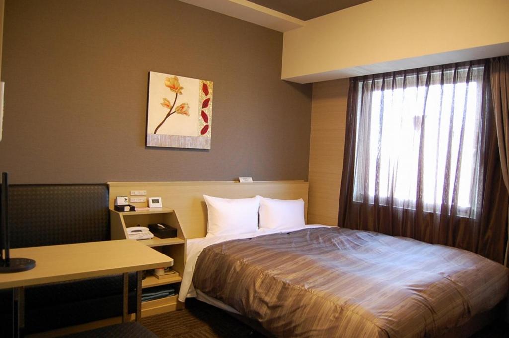 丰田市Hotel Route Inn Toyota Motomachi的配有一张床、一张书桌和一扇窗户的酒店客房