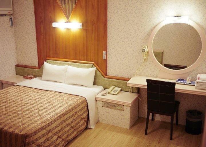 苗栗市绿庭商务旅馆的酒店客房,配有床和镜子