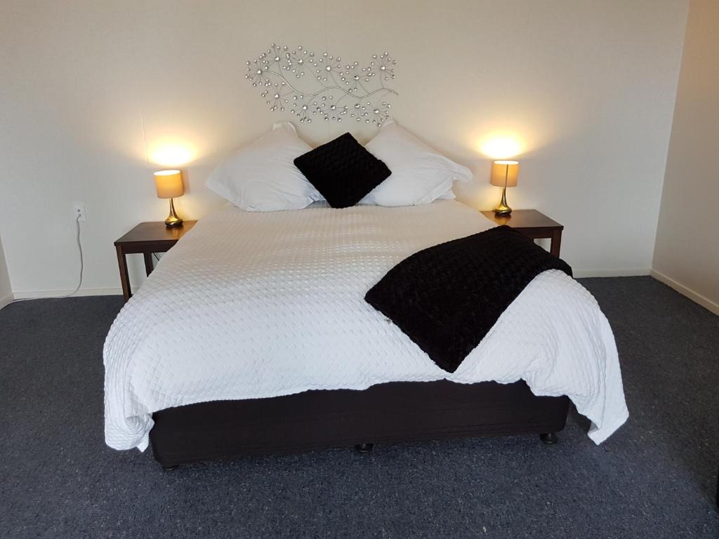 努盖特角卡卡角迈克&珍妮旅馆 的一间卧室配有一张带两盏灯的大型白色床。