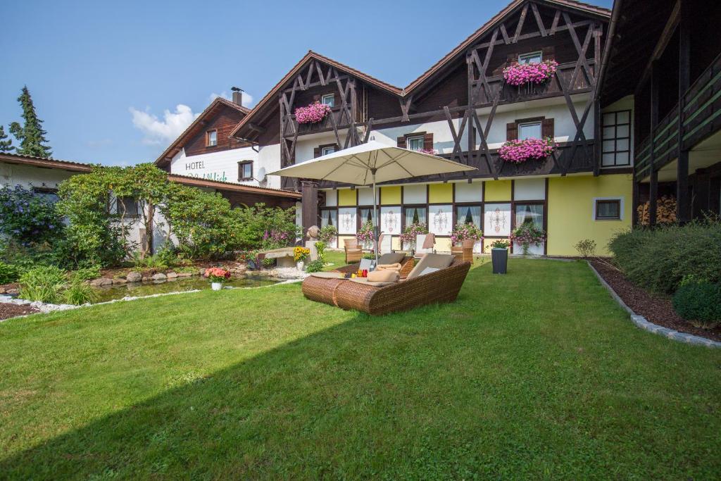 博登迈斯Hotel Waldblick的一个带草坪、沙发和遮阳伞的房子