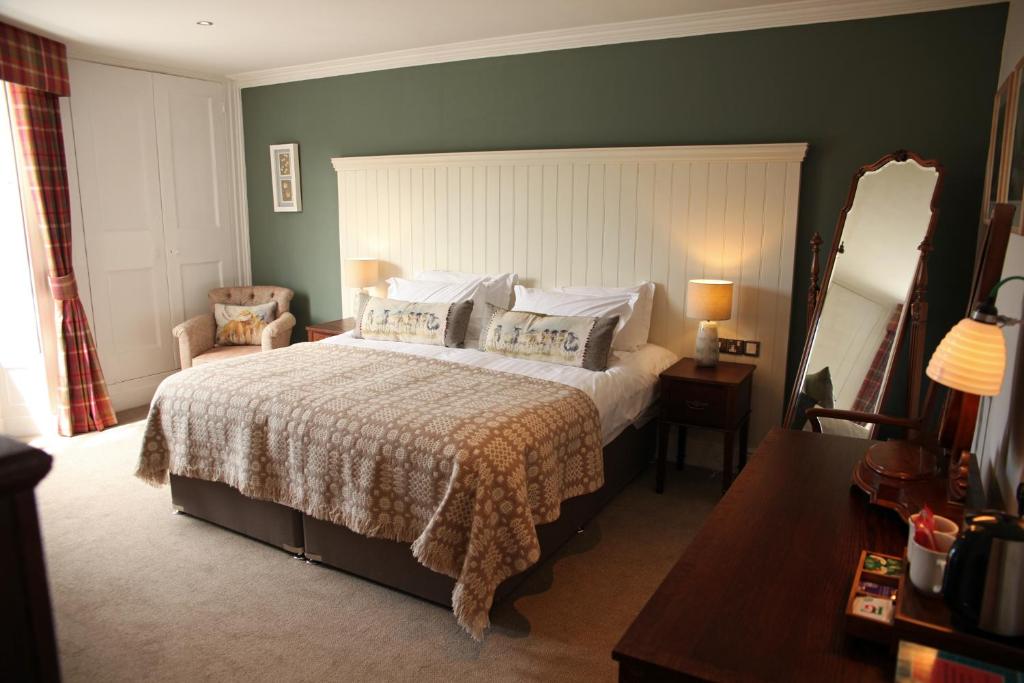 康威艾尔斯奇恩阿姆斯宾馆的一间卧室配有一张大床和镜子