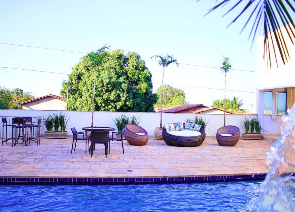 阿拉瓜伊纳Mais Hotel的游泳池旁带桌椅的天井