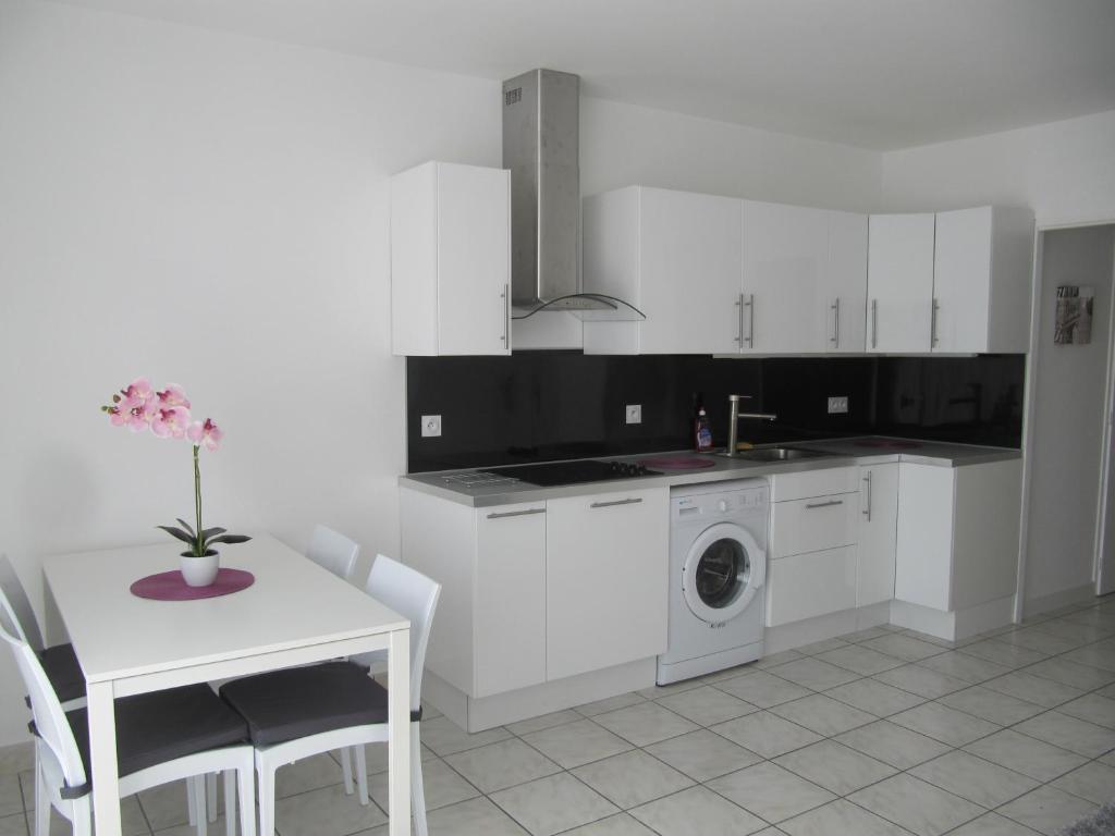 雅莱地区圣梅达尔Clos Saint Médard的白色的厨房配有桌子和洗衣机。
