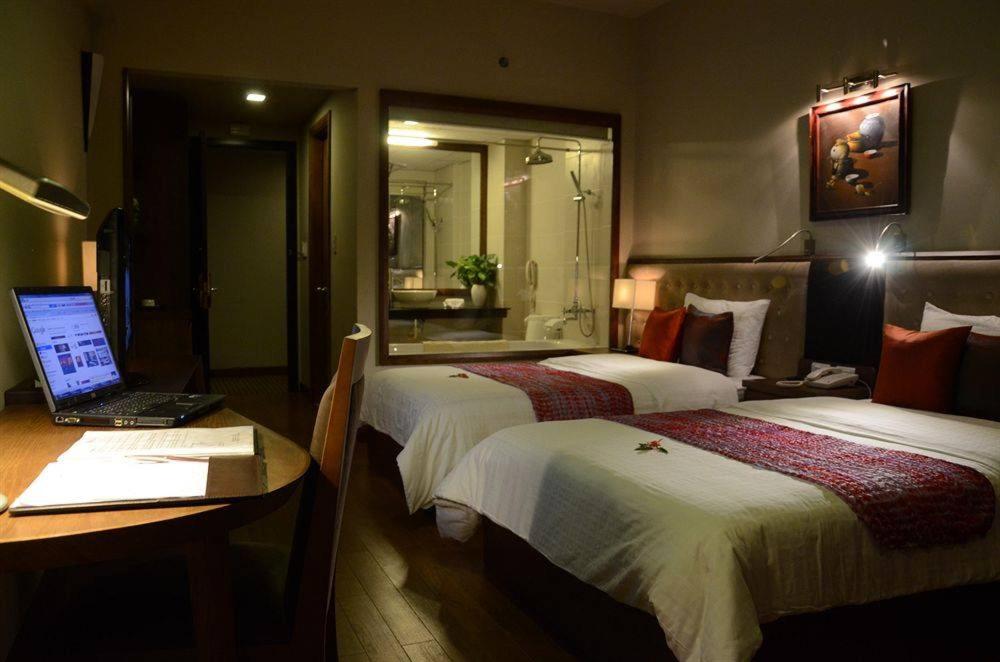 顺化顺化亚洲大酒店的酒店客房设有两张床和一张书桌上的笔记本电脑
