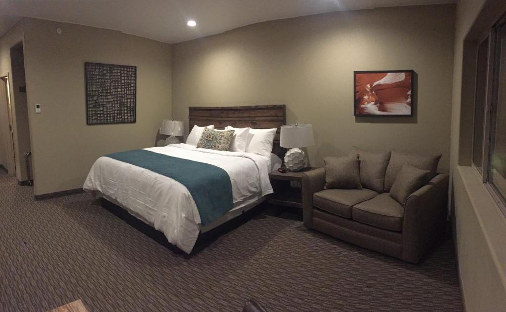 埃斯卡兰特Canyon Country Lodge的一间卧室配有一张床、一张沙发和一把椅子