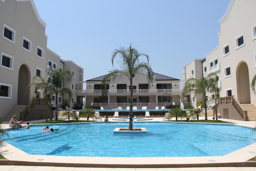 福尔摩沙Howard Johnson Hotel & Casino的一座大型游泳池,在一座建筑前方有一棵棕榈树