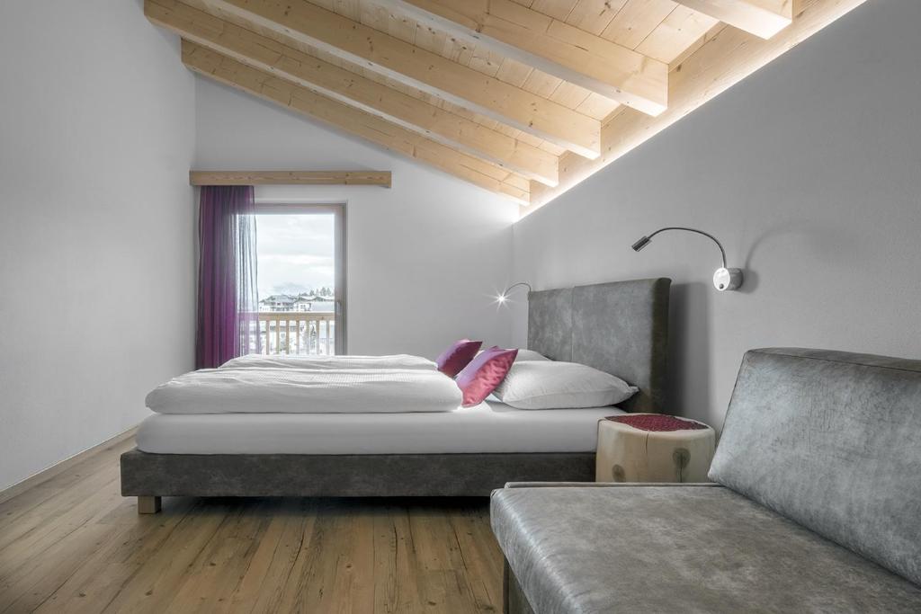 圣卡夏诺Ciasa de Lenz的一间卧室配有一张床、一张沙发和一个窗口