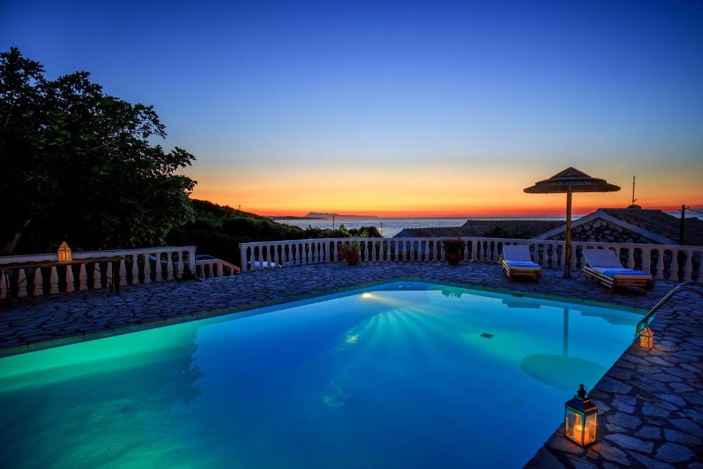 圣斯特凡诺斯Find Tranquility at Villa Quietude A Stunning Beachfront Villa Rental的一座享有日落美景的游泳池