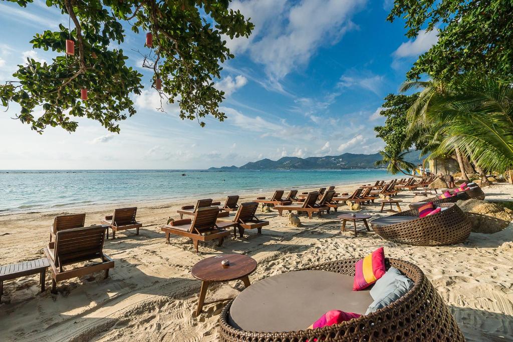 查汶Muang Samui Spa Resort - SHA Extra Plus的海滩上设有桌椅,大海上设有沙滩