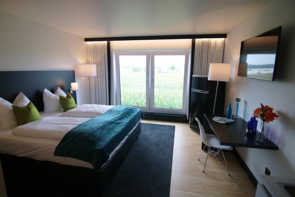 明德尔海姆MN Hotel by WMM Hotels的配有一张床、一张书桌和一扇窗户的酒店客房