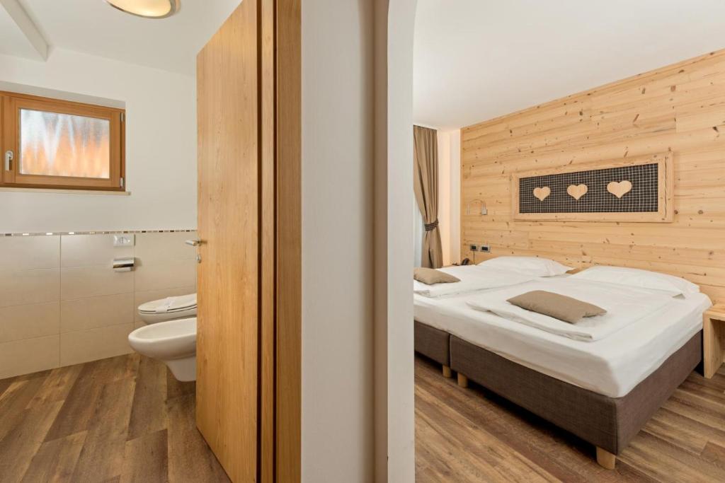 博萨迪法萨Hotel Garni Lastei的一间卧室设有一张床和一间浴室。