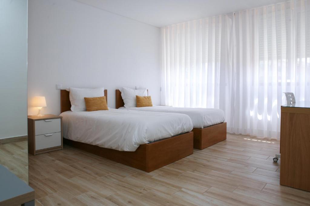 圣若昂达马德拉Central Suites的一间卧室配有一张铺有木地板的白色床单。