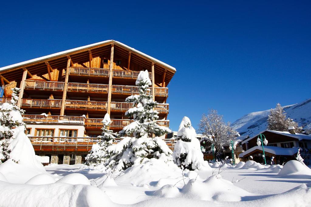 莱德萨阿尔卑斯Vacancéole - Résidence Cortina的前面有雪覆盖的树木的滑雪小屋