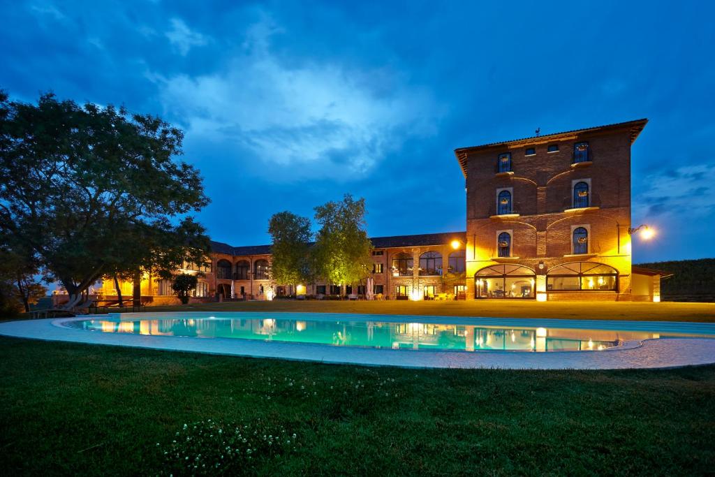 MontemagnoTenuta Montemagno Relais & Wines的一座大型建筑,在晚上前设有一个游泳池