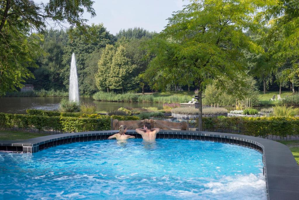 巴特纽维斯Thermen Bad Nieuweschans的两人在带喷泉的花园的游泳池里