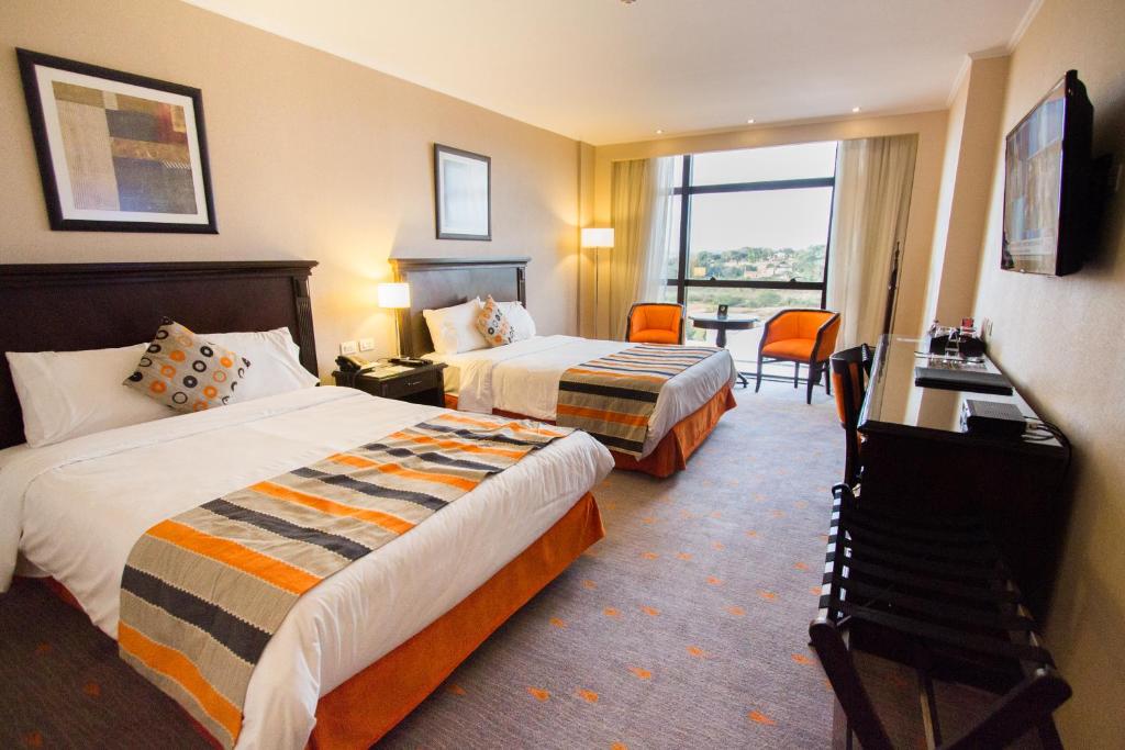 恩卡纳西翁狂欢节赌场酒店 的酒店客房设有两张床、一张书桌和一个窗户。