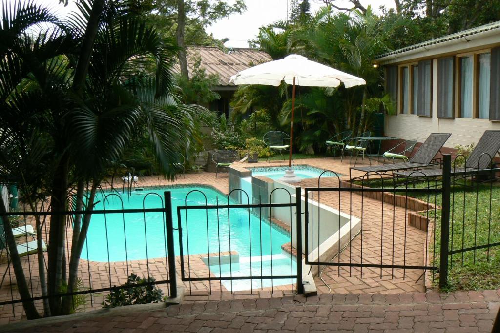 圣卢西亚Fisheagle Accommodation的一座房子旁带遮阳伞的游泳池
