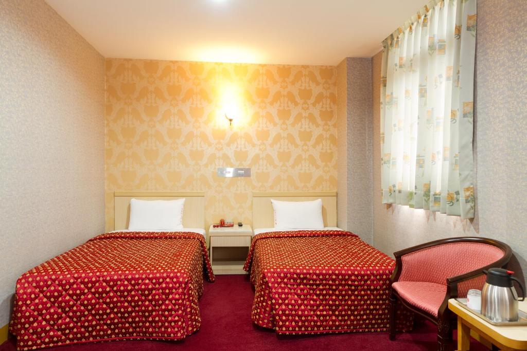 高雄嵩山大饭店 的酒店客房,配有两张床和椅子