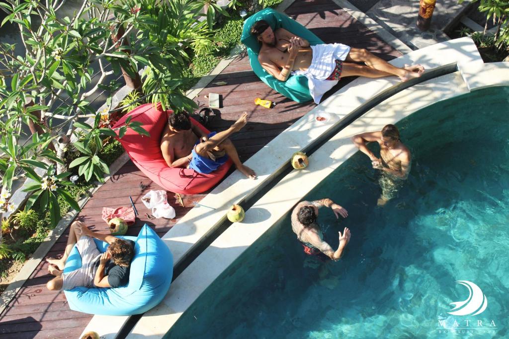 坎古巴厘岛马特拉冲浪营旅馆的一群人躺在游泳池周围