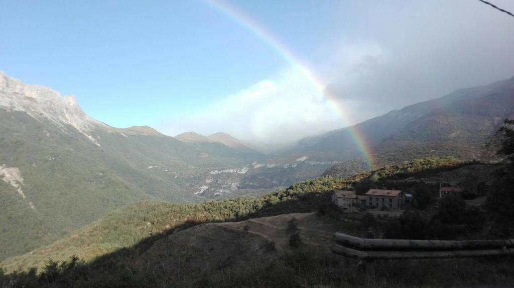 LamianaHotel de Montaña Lamiana的山丘上一座房子的山谷上空的彩虹
