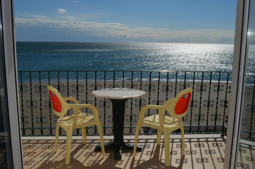 多列毛利诺斯普拉萨玛尔公寓的阳台配有一张桌子和两把椅子,享有海景