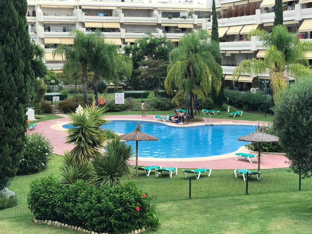 马贝拉Apartament Guadalmina的度假村内带椅子和遮阳伞的游泳池