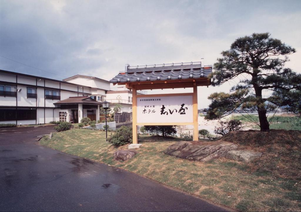 佐渡市志屋日式旅馆的一座有树的建筑前面的标志
