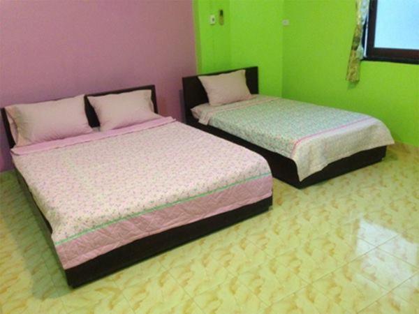 夜功府Royal Land Mae Klong Hotel的配有两张床铺的客房,拥有绿色和粉红色的墙壁