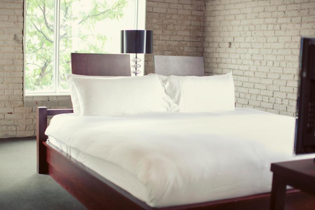 多伦多奥绸酒店的卧室内的一张带白色床单和枕头的床
