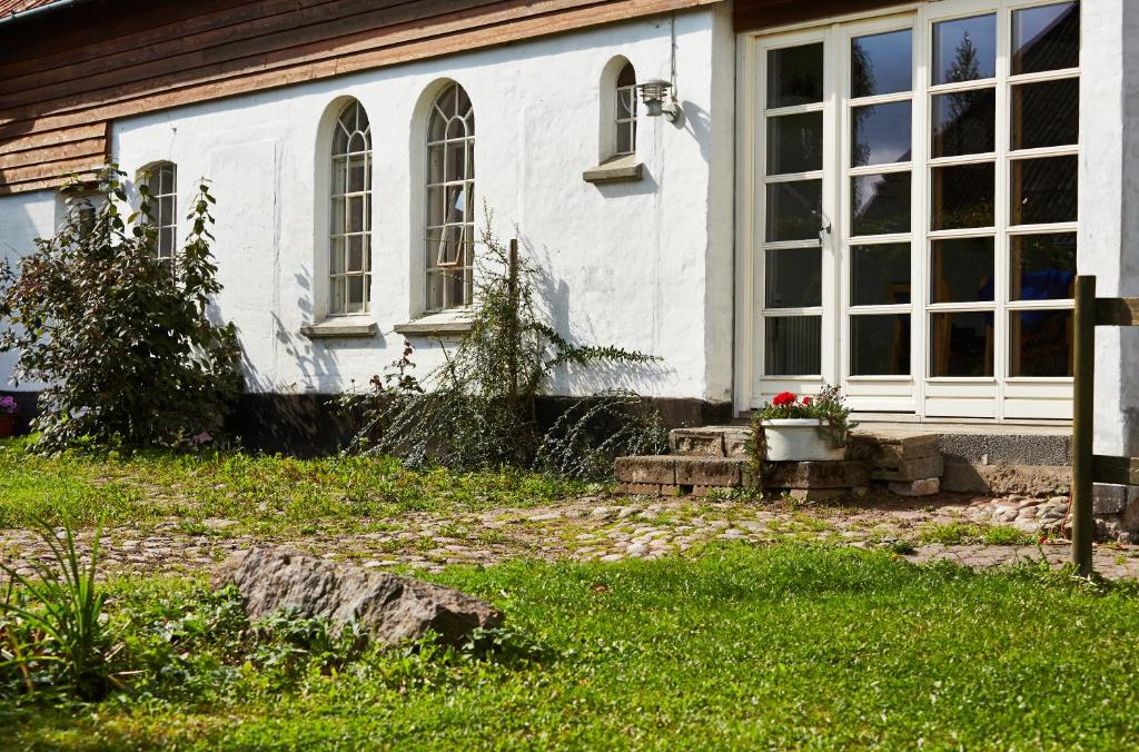 SkovsgårdeRosenlund Bed & Breakfast的一间白色的房子,设有窗户和庭院内的长凳