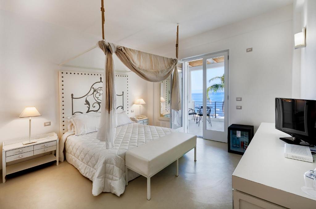 利帕里Hotel Villa Enrica - Aeolian Charme的一间白色的卧室,配有天蓬床和电视