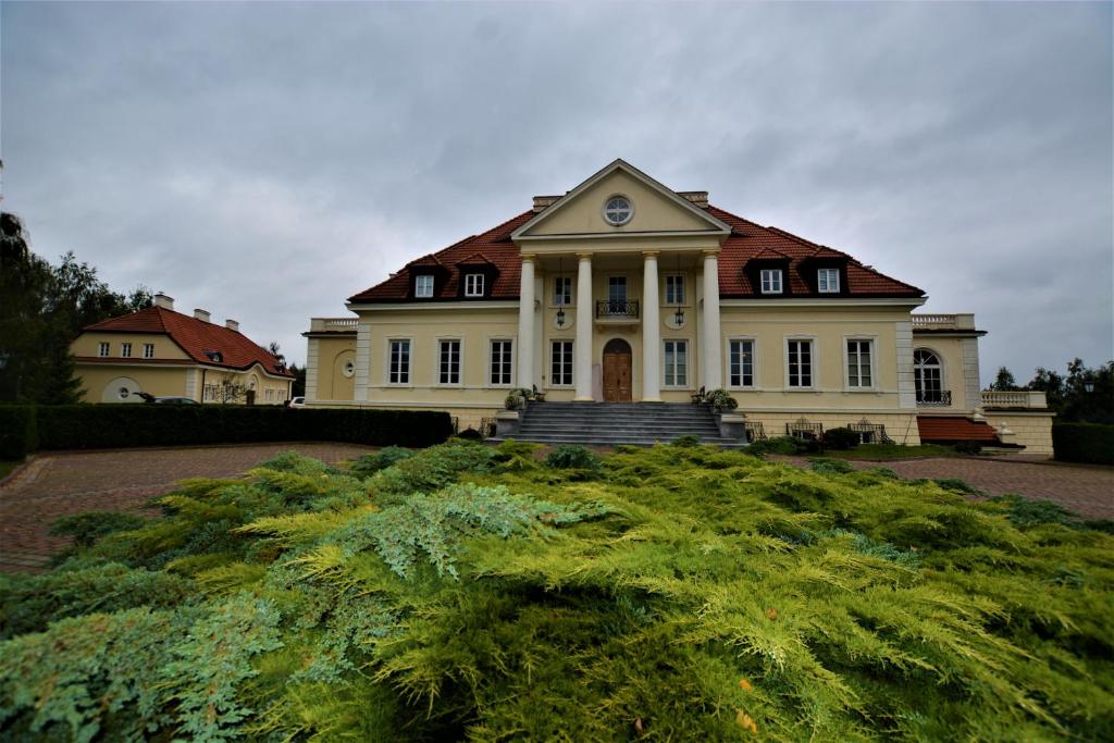 PniewyDwor Osieczek的一座白色的大房子,上面有时钟
