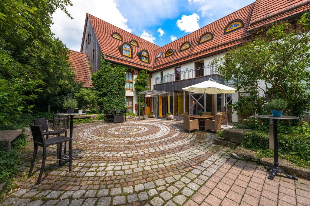 纽伦堡辛德勒霍夫酒店的庭院内有带桌子和雨伞的建筑