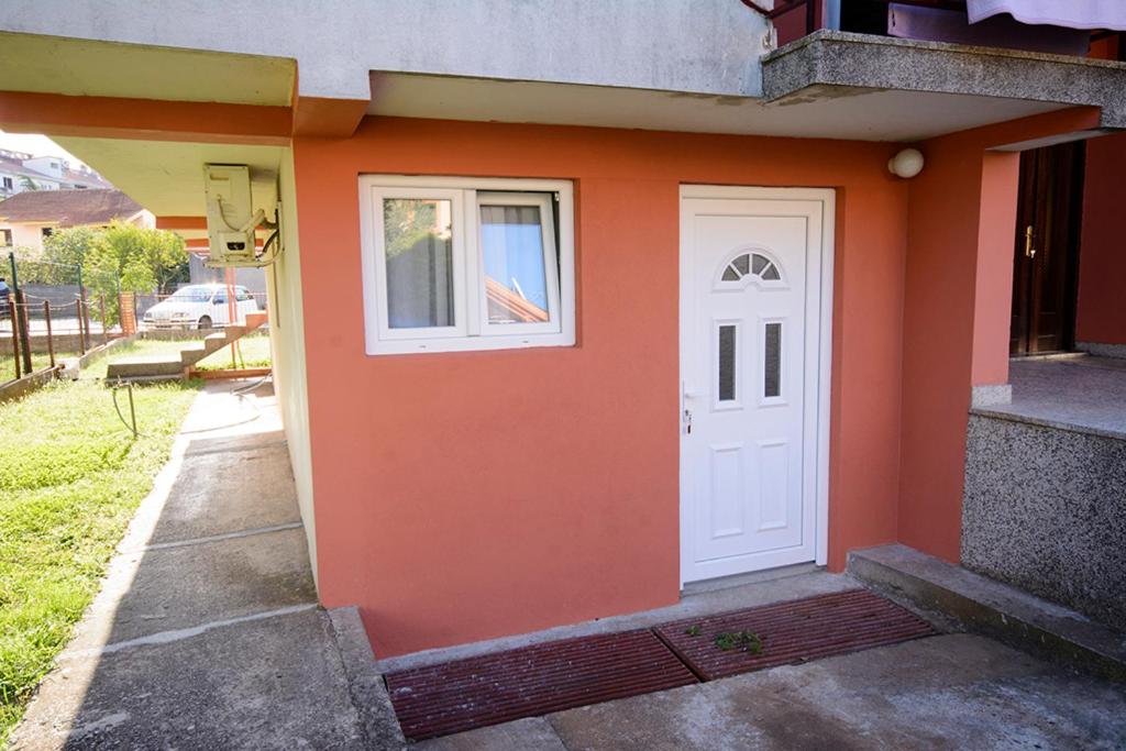 波德戈里察Apartments Popovic的橙色的建筑,有白色的门和窗户