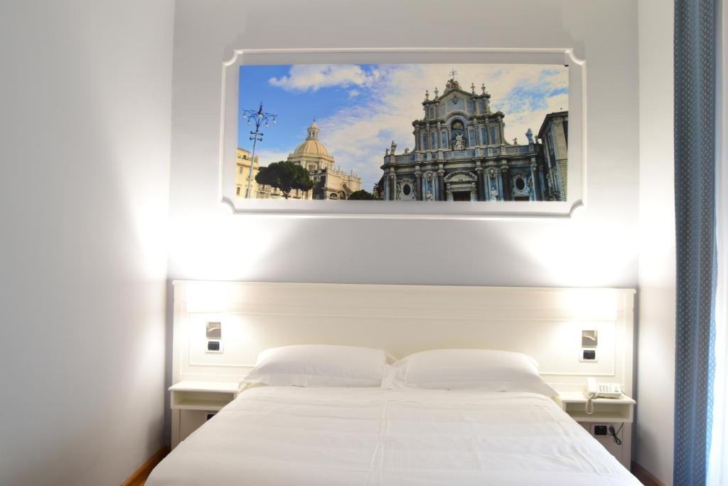 卡塔尼亚中央酒店的卧室配有一张白色床,墙上挂着一幅画