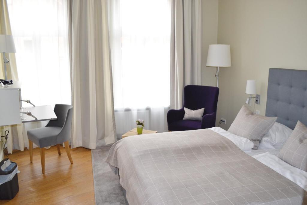 吕讷堡Hotel Zum Roten Tore的一间卧室配有一张床、两把椅子和一张书桌