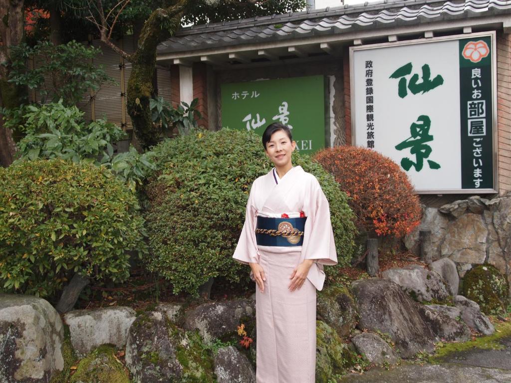 箱根仙景酒店的站在建筑物前的和服上的女人
