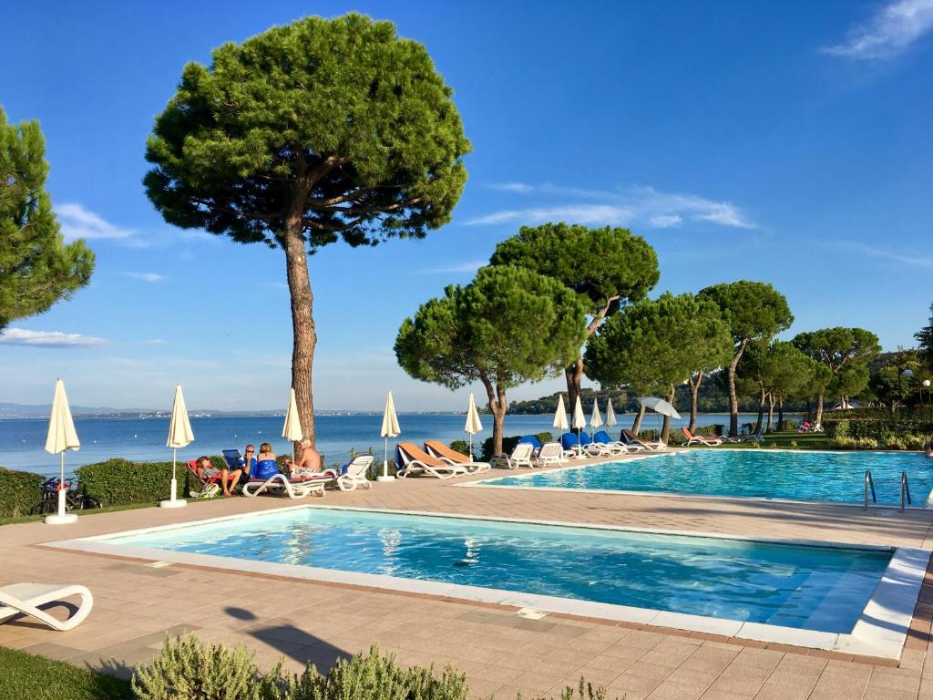 加达湖畔帕登赫戴尔拉戈度假酒店的一座种有树木的游泳池,一座背景为大海的游泳池