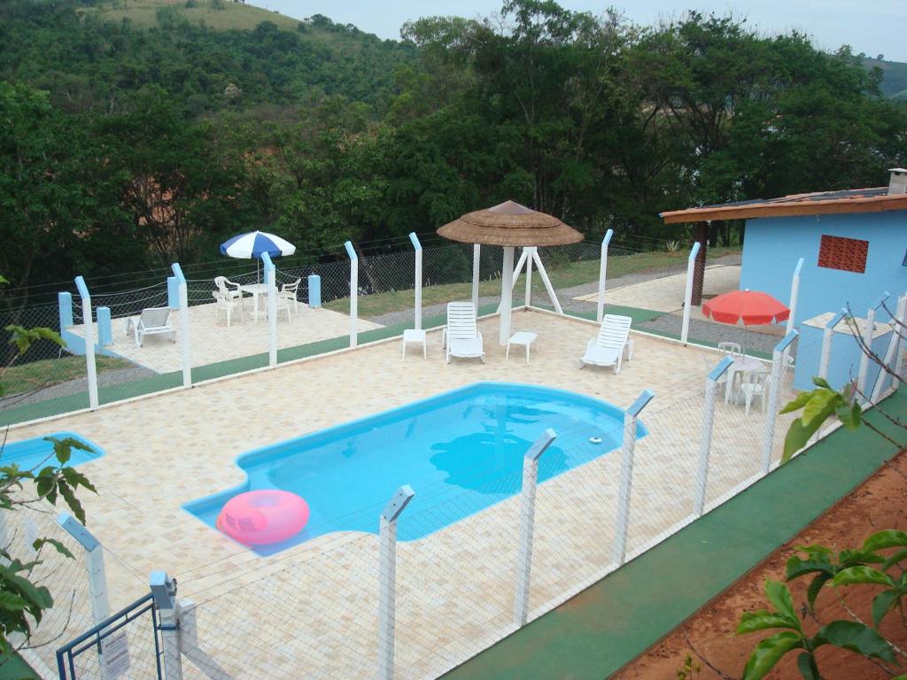 卡孔德Recanto Bela Vista的房屋旁的游泳池配有椅子和遮阳伞