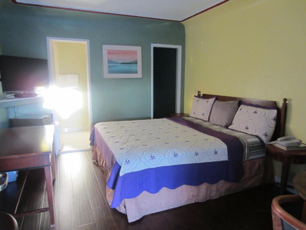 长滩游鹰经济型汽车旅馆的一间卧室配有一张床、一张桌子和一盏灯