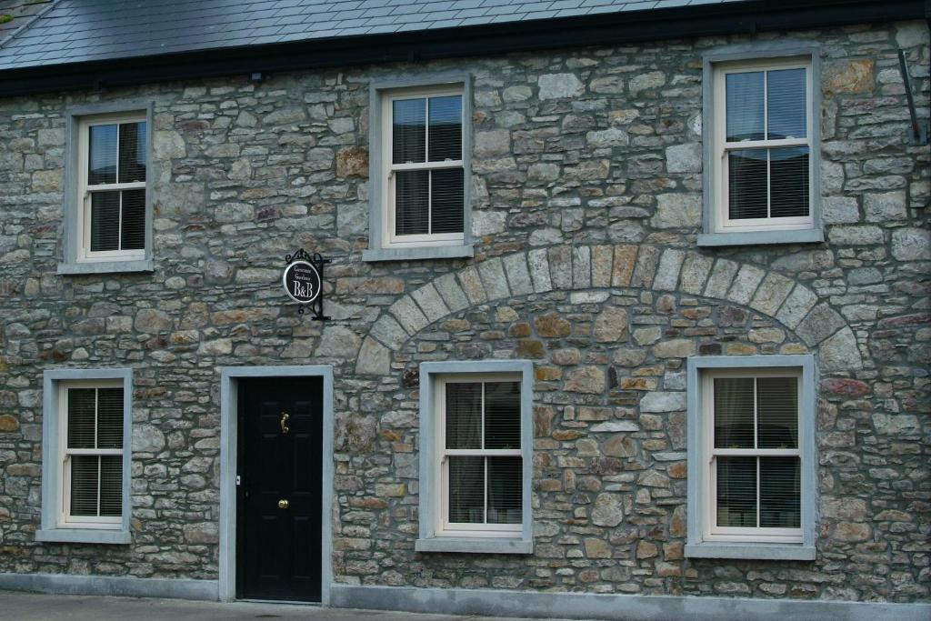 查尔斯敦Cornerstone 2 Bed Townhouse的一座石制建筑,设有白色的窗户和黑色的门