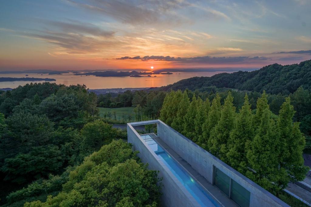 松山SETOUCHI RETREAT by Onko Chishin的享有日落美景的房屋设有游泳池