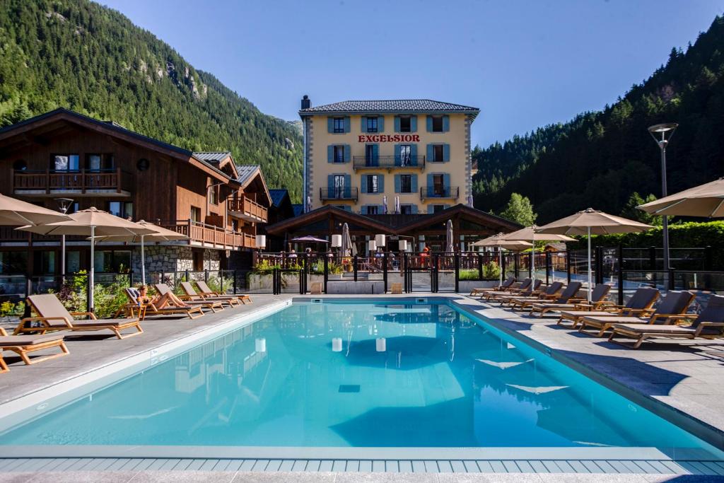 夏蒙尼-勃朗峰Excelsior Chamonix Hôtel & Spa的一座带椅子的游泳池和一座建筑的酒店