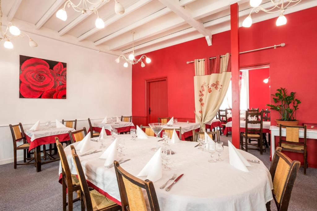 YssingeauxLogis Hotel Restaurant Le Cygne的一间设有白色桌椅和红色墙壁的餐厅