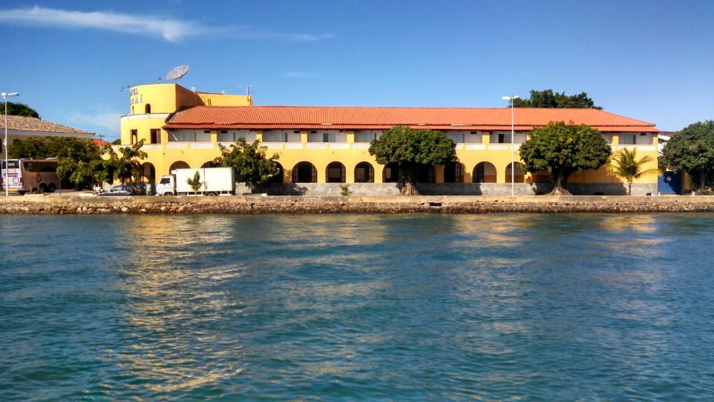 伊塔帕里卡Hotel Icaraí的水边有红色屋顶的黄色建筑